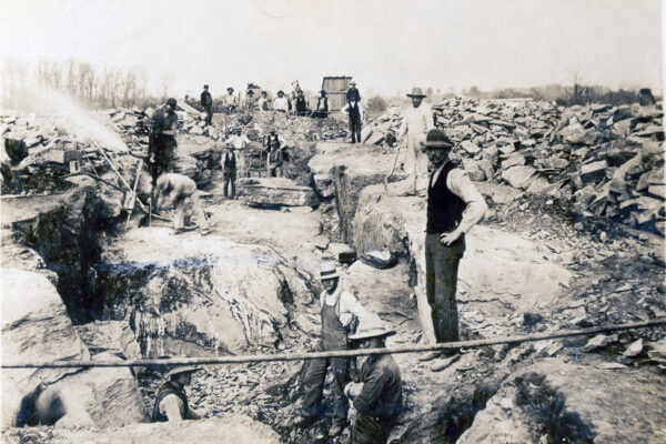 Workers use shovels and a jackhammer to dig the foundation.