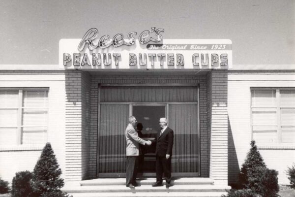 Photo of two men shaking hands in front of a building marked Reese's Peanut Butter Cups
