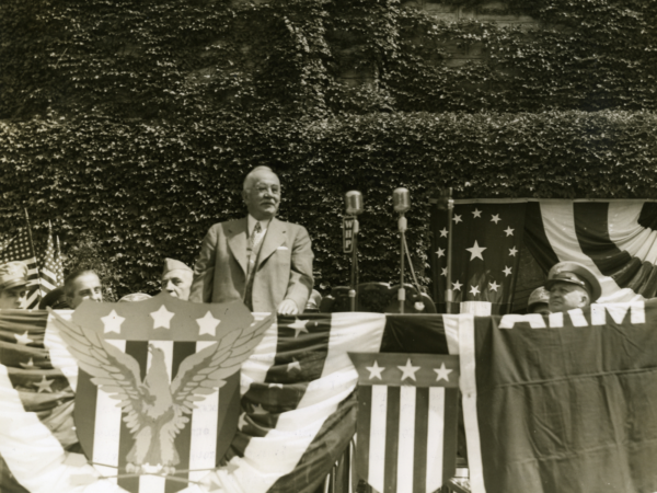 Milton Hershey giving a speech on a patriotic stage