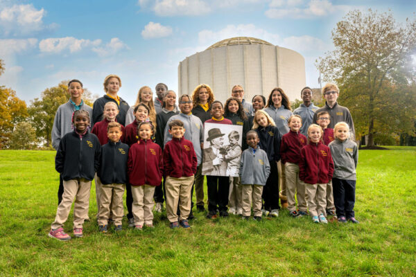 Milton Hershey School students in front of Founders Hall with Milton and the Boy portrait canvas